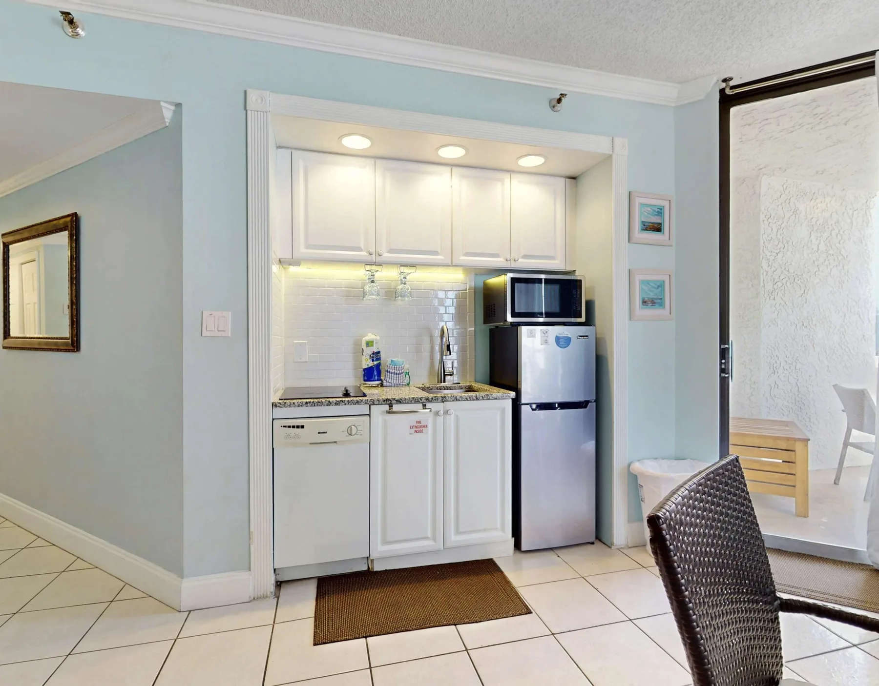 A compact kitchen with white cabinets, a refrigerator, and a microwave.