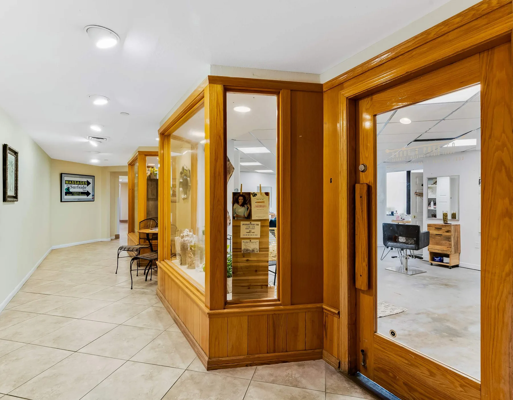 Shared amenity: A tiled hallway runs beside wood-framed glass partitions and a glass door.