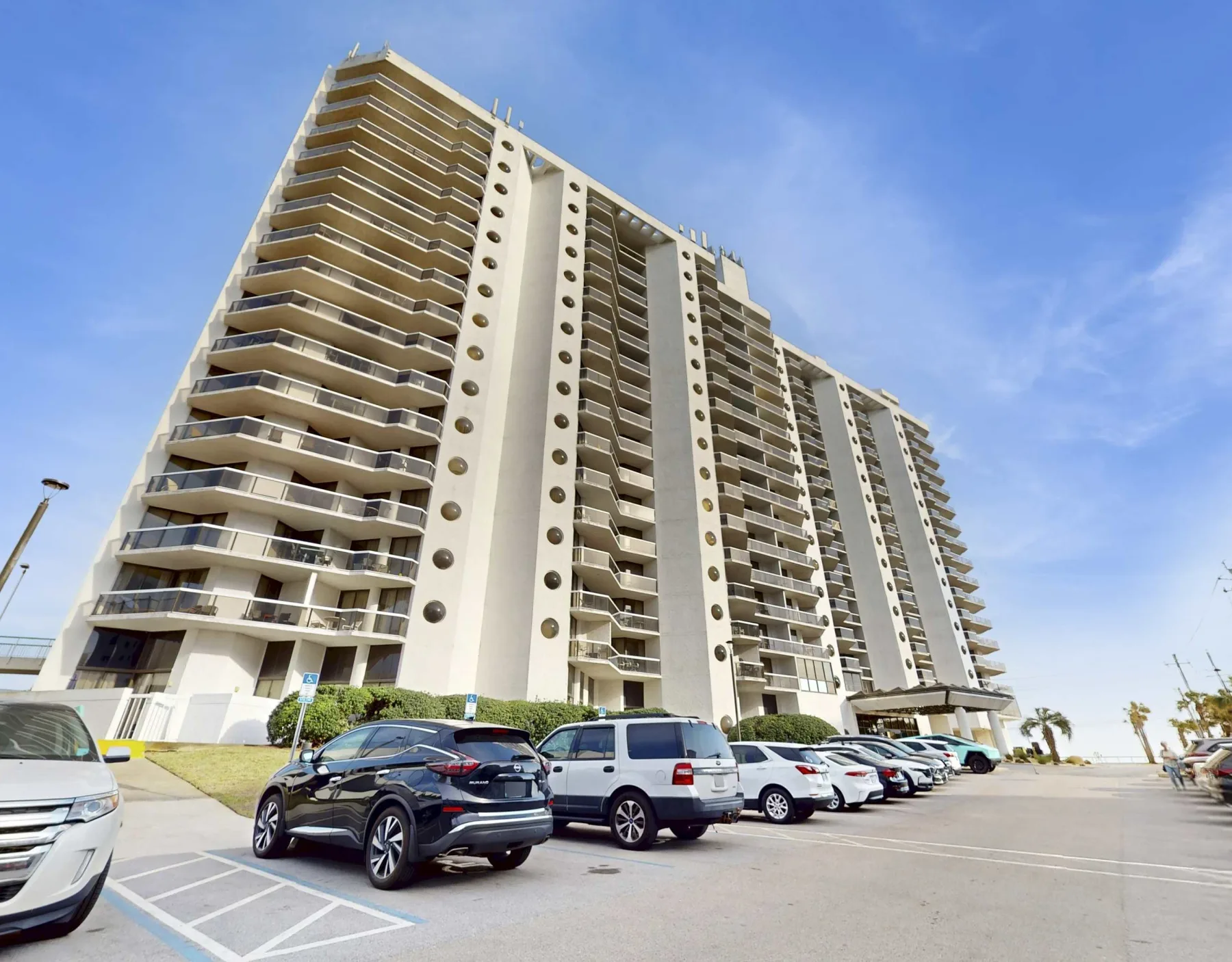 Shared amenity: A high-rise apartment building with parked cars along the front.