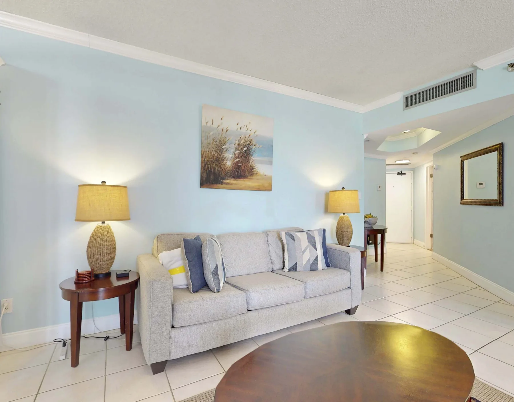 A living room with a light-colored sofa, side tables, and lamps.