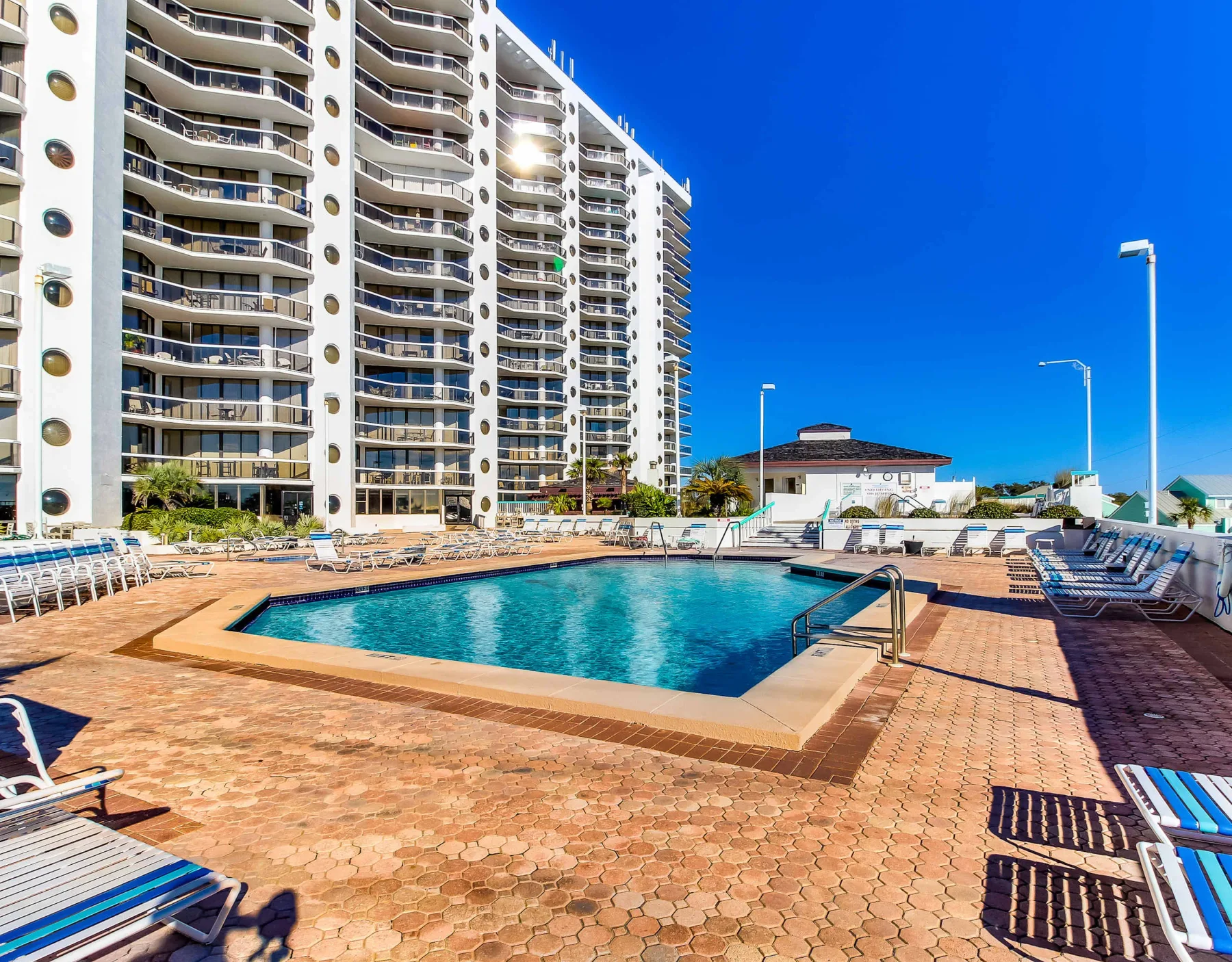 Shared amenity: Outdoor swimming pool surrounded by lounge chairs beside tall apartment buildings.