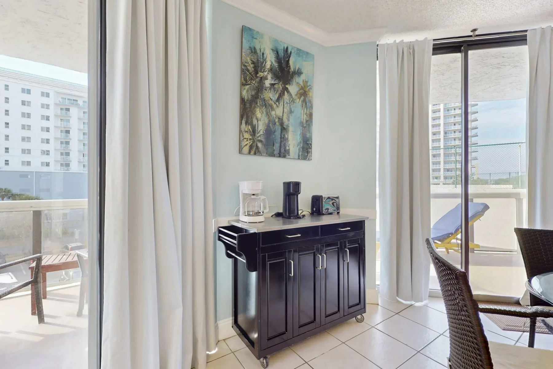 A bright dining area with a dark sideboard and large windows.