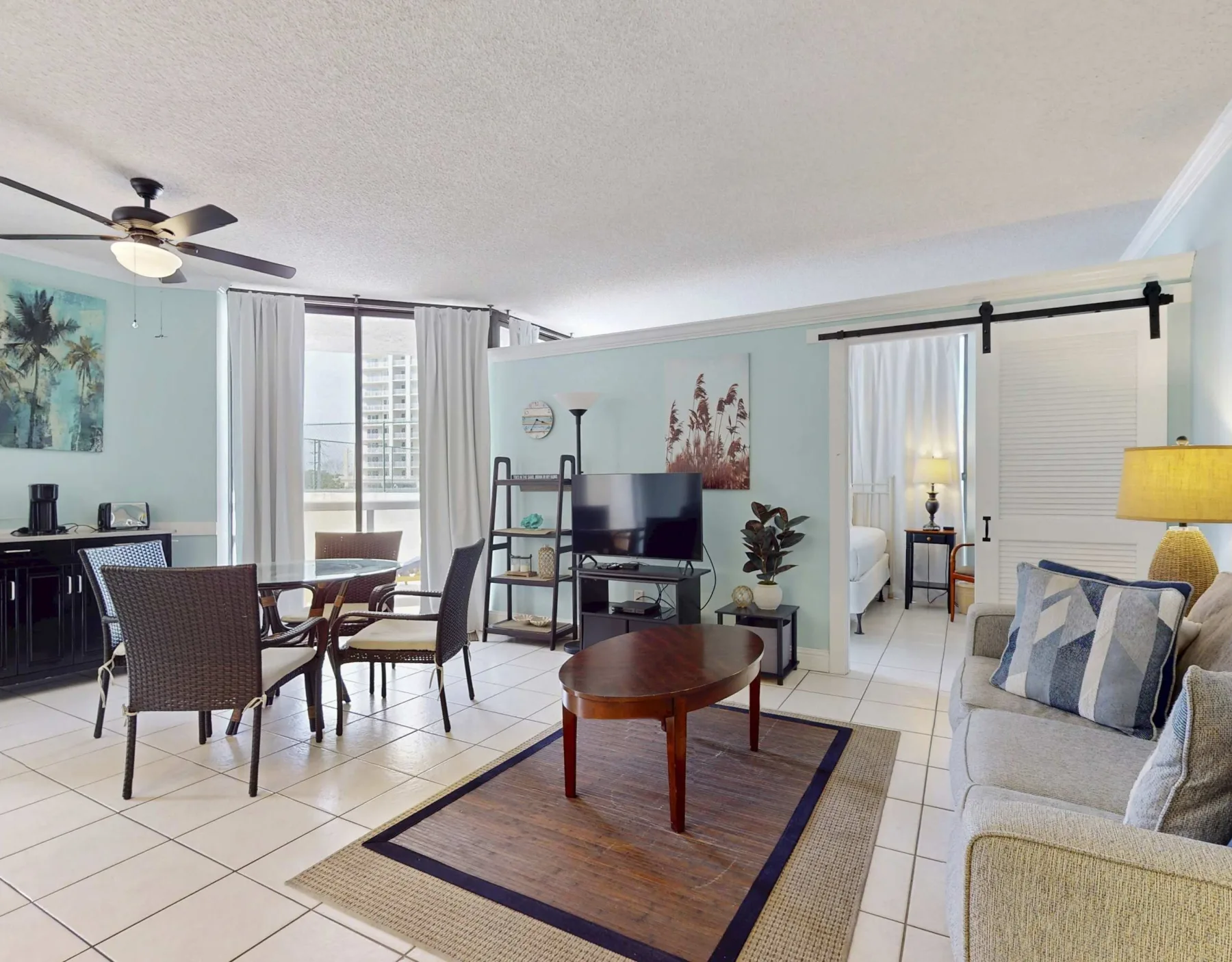 A bright living and dining area with seating, a television, and large windows.