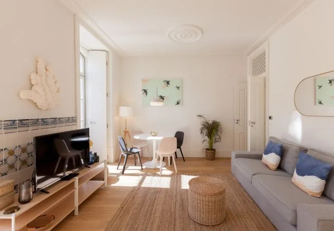 Una sala luminosa con mesa de comedor, asientos y un televisor.