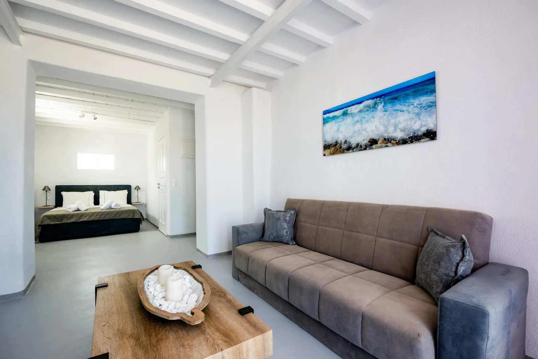 Una sala luminosa con un sofá gris y una mesa de centro de madera.