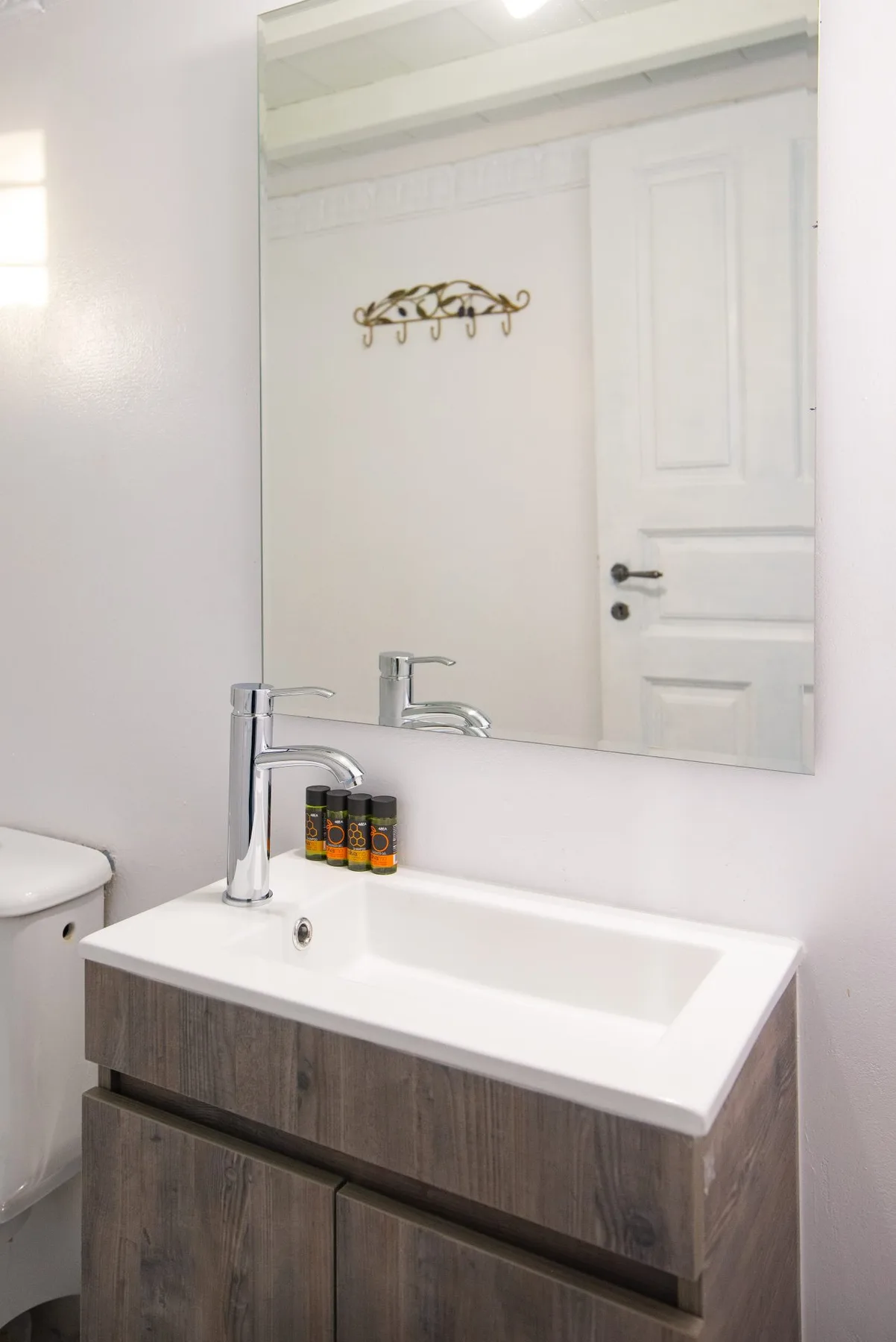 Un tocador de baño con lavabo blanco, grifos cromados y un espejo grande.