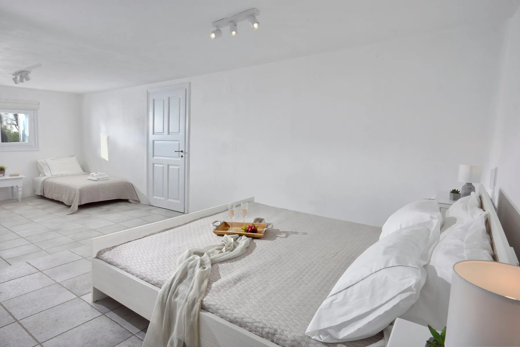 Un dormitorio luminoso con dos camas y una bandeja pequeña sobre la cama del primer plano.