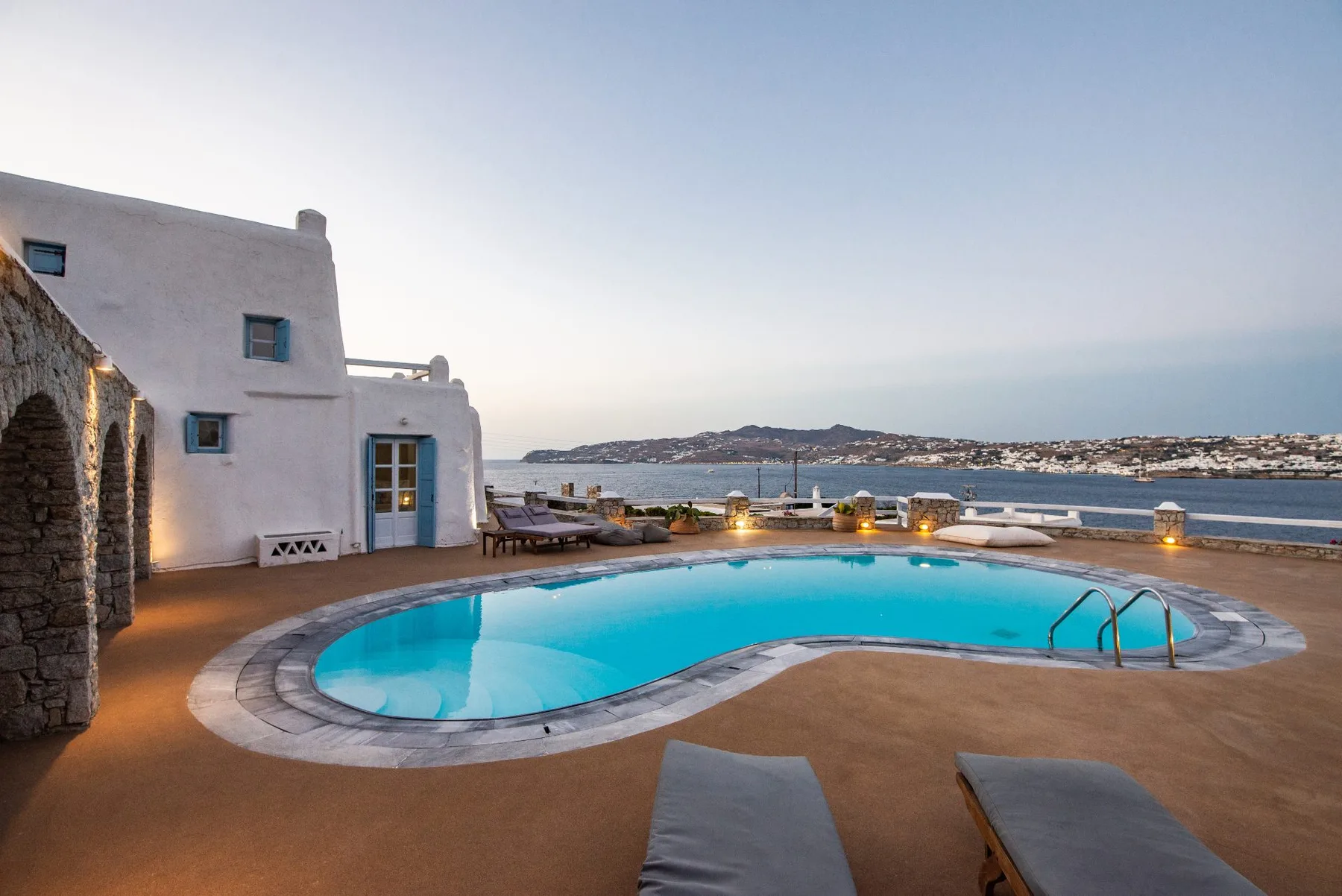 Una piscina junto a edificios blancos tiene vistas al mar.