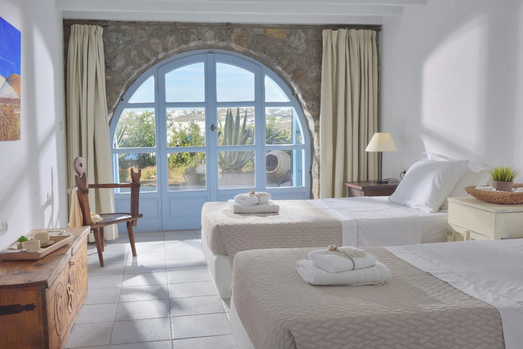 Un dormitorio luminoso con dos camas y una gran ventana arqueada.