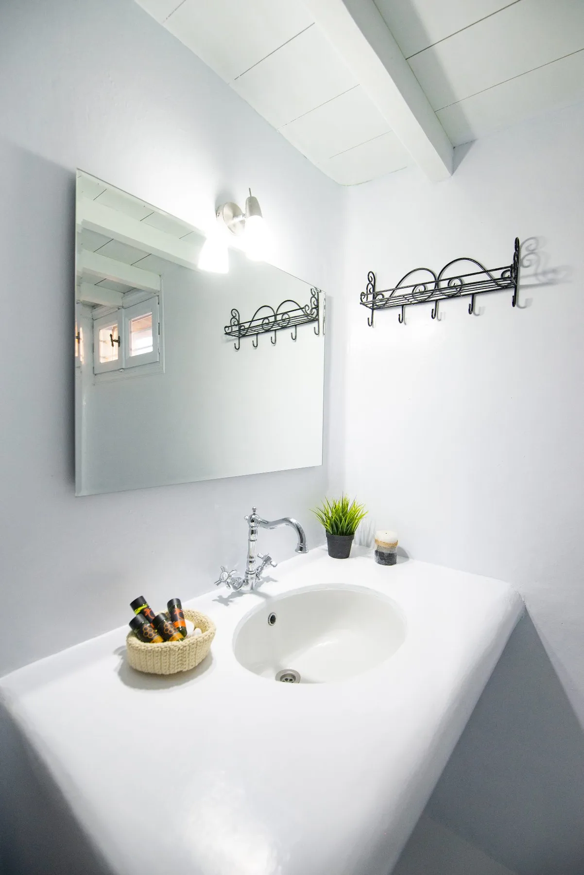 Un lavabo de baño con espejo en la pared y ganchos para colgar.