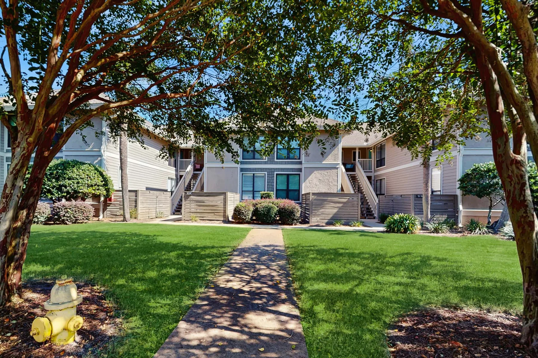 Shared amenity: A landscaped lawn and walkway lead toward a row of residential buildings.
