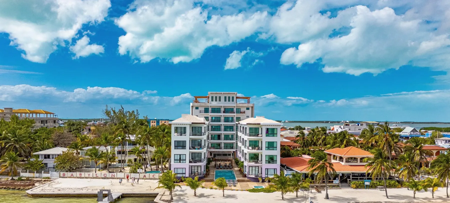 Espacio representativo del hotel: Un edificio hotelero se encuentra entre palmeras bajo un cielo parcialmente nublado.
