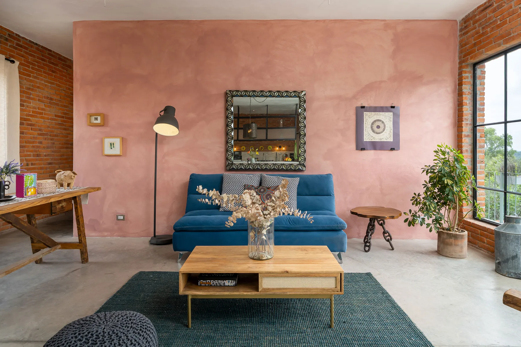A living room with blue seating, a coffee table, and a pink accent wall.