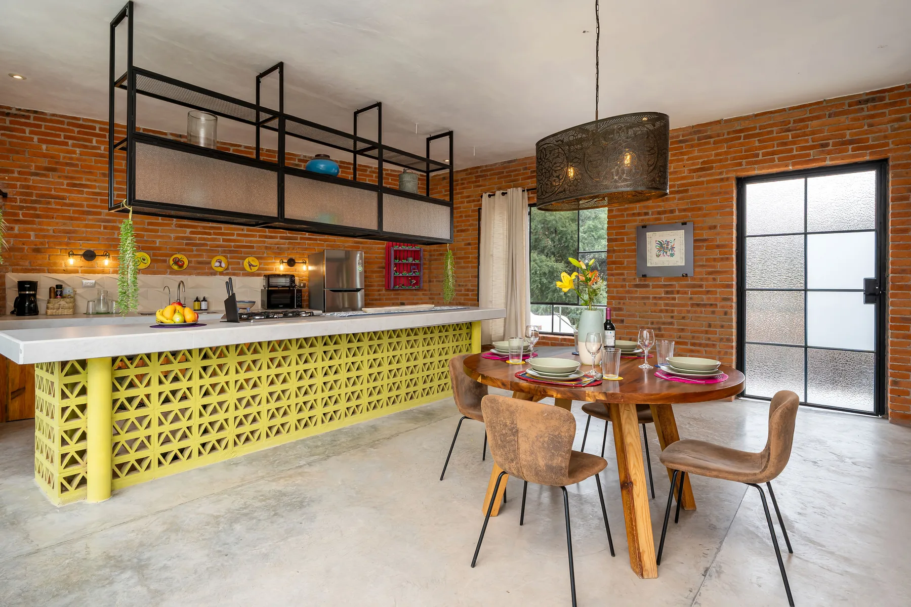A dining area with a round table beside a kitchen with a yellow patterned counter.