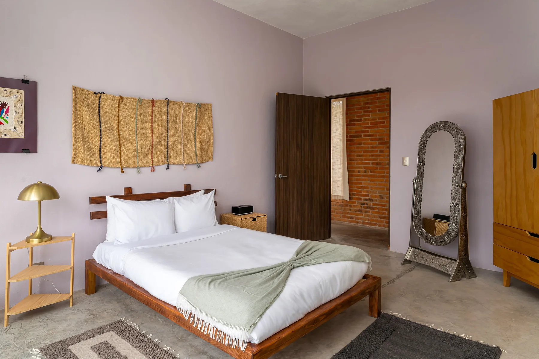A bedroom with a neatly made bed and a wooden headboard.