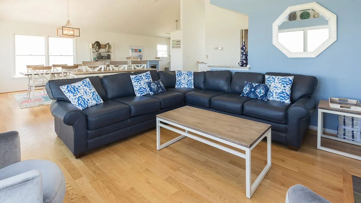 A living room with a dark sectional sofa, patterned cushions, and a coffee table.