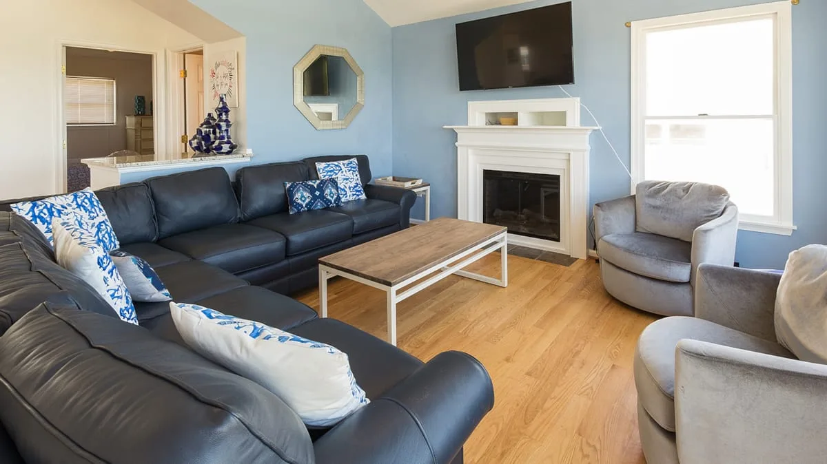 A living room with dark seating, a fireplace, and a television.