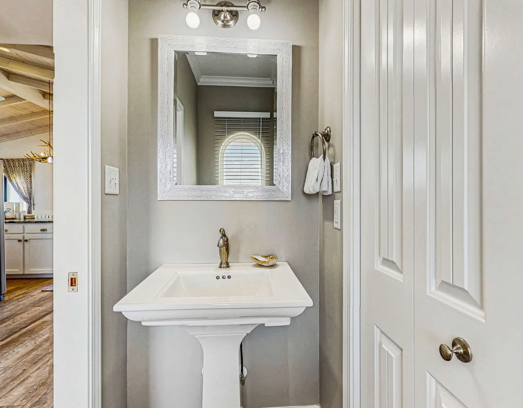 A small bathroom with a pedestal sink and mirror.