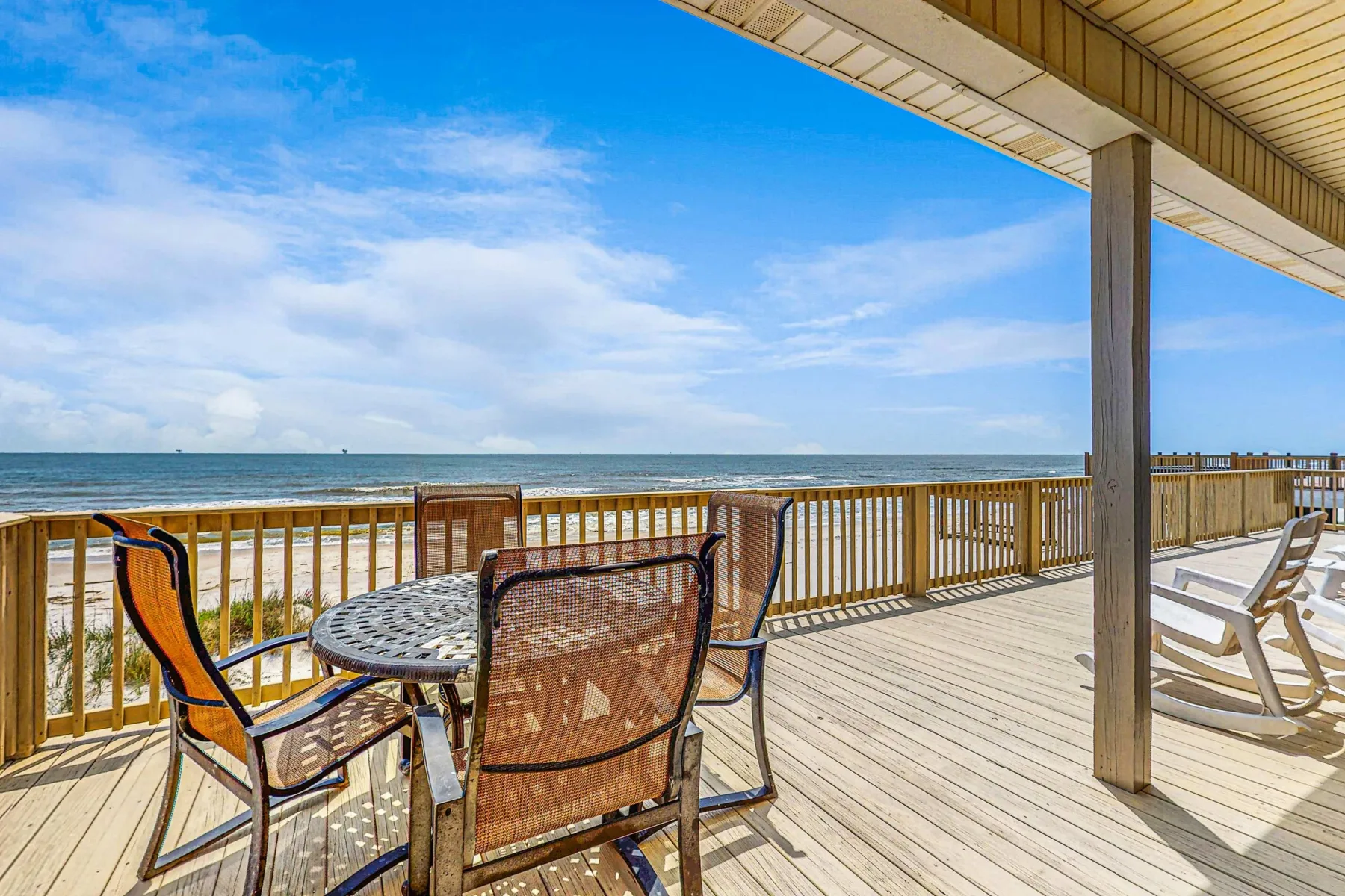 A seaside deck with outdoor seating overlooks the ocean.