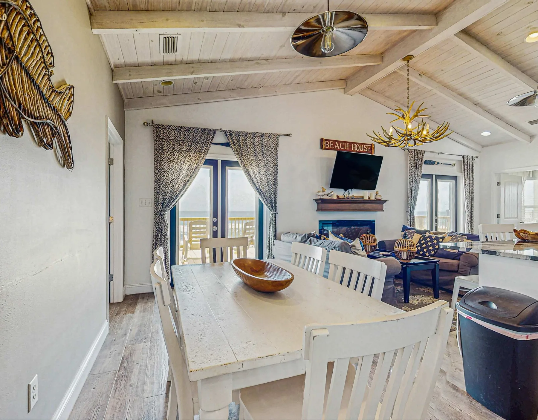 A bright dining and living area with a long table and seating by the windows.