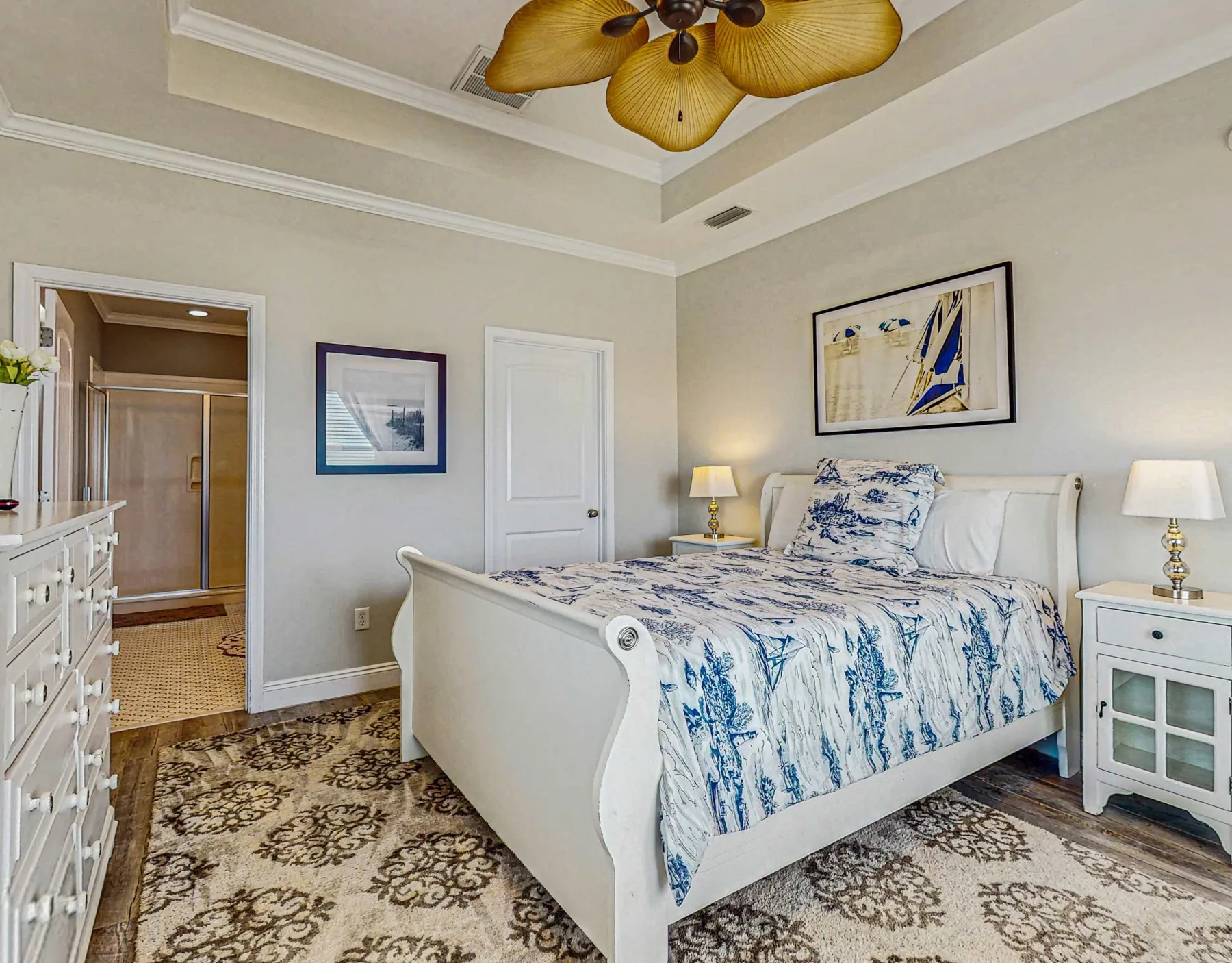 A bedroom with a bed dressed in blue-and-white bedding and matching bedside tables.