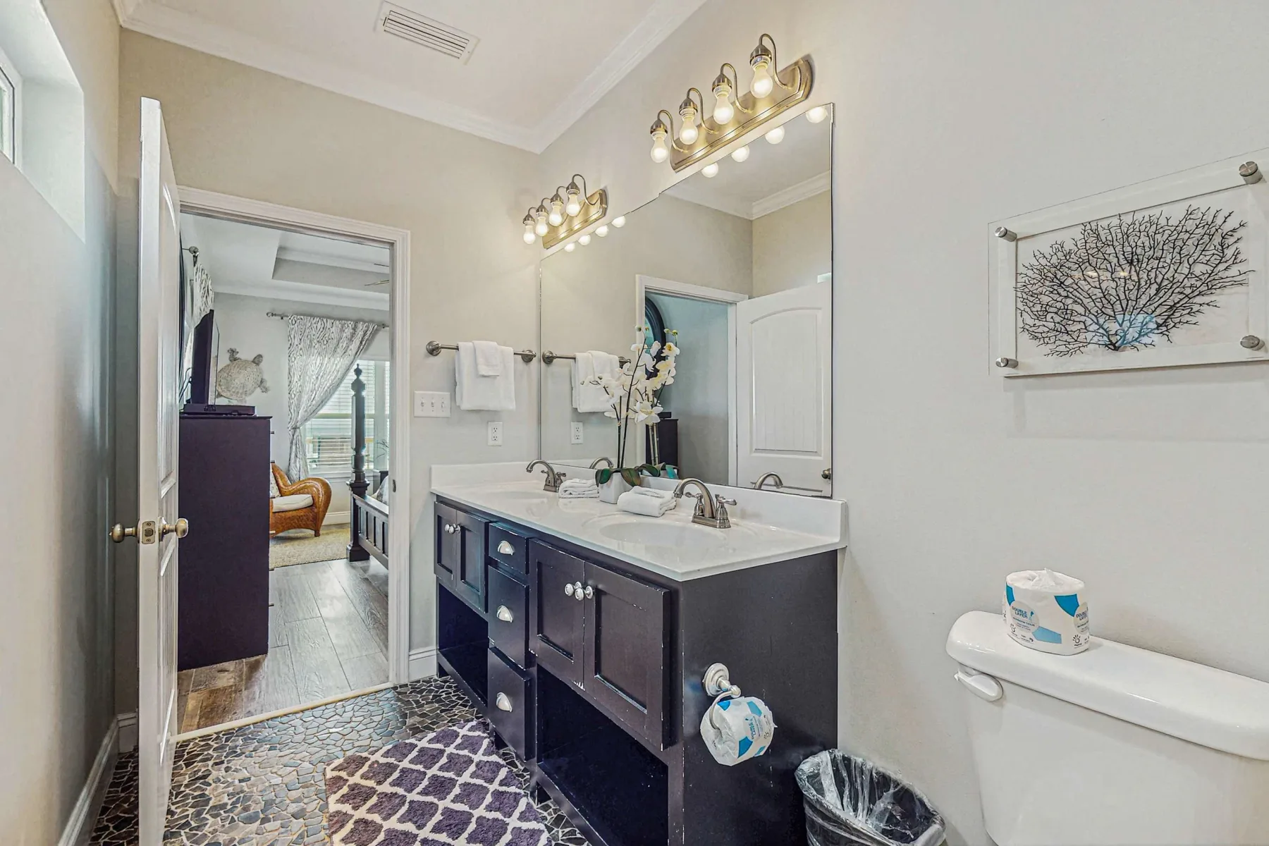 A bathroom vanity with a large mirror and light fixtures above it.