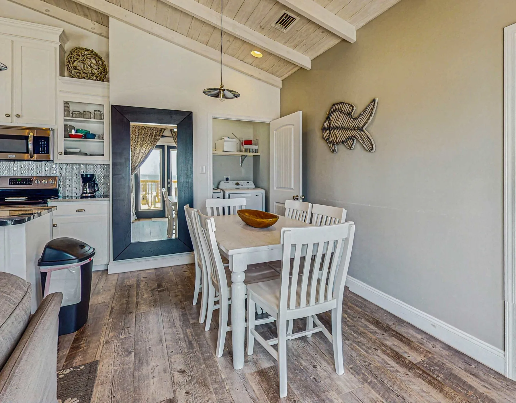 A dining area with a white table and chairs beside a compact kitchen.