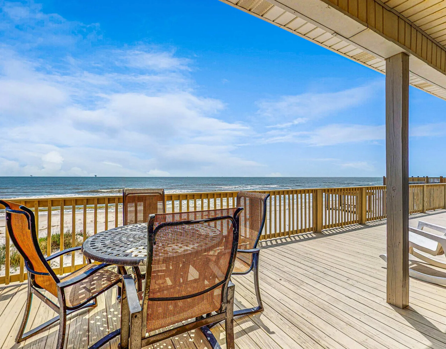 A seaside deck with outdoor seating overlooks the ocean.