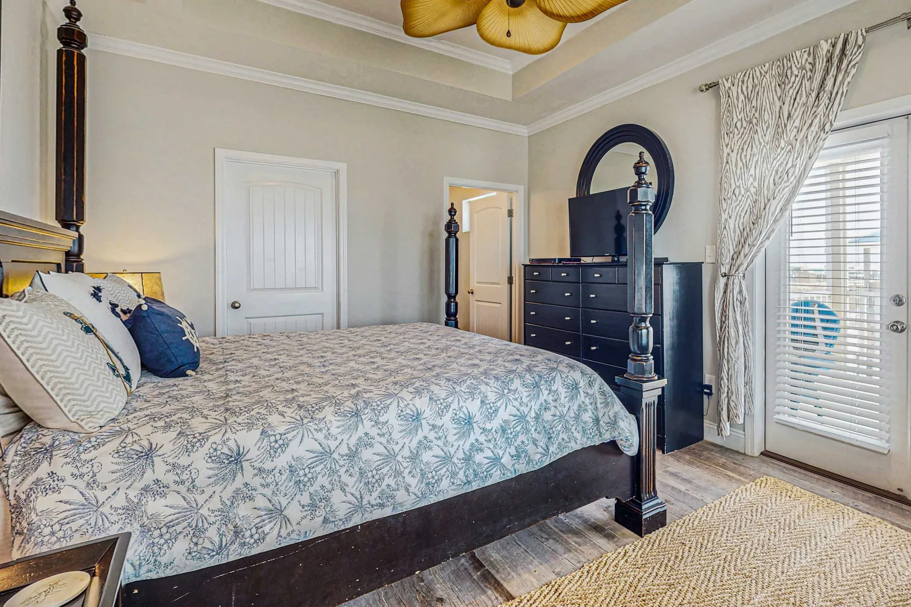 A bedroom with a large bed, dresser, and curtained glass door.