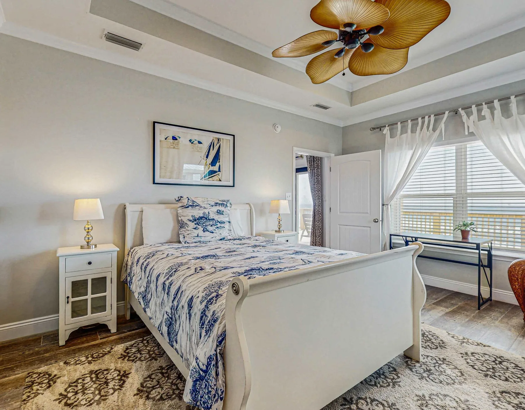 A bright bedroom with a bed dressed in blue-and-white patterned bedding.