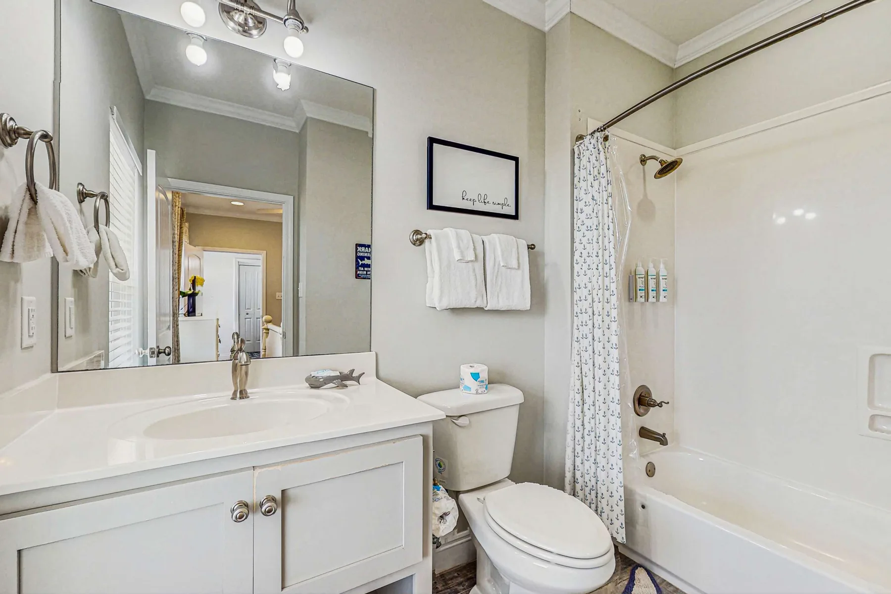 A bright bathroom with a sink vanity, toilet, and bathtub with a shower.