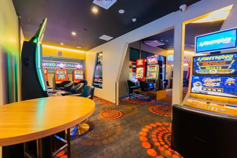 Espacio representativo del hotel: Una zona de arcade interior con máquinas de videojuegos iluminadas y una mesa redonda.