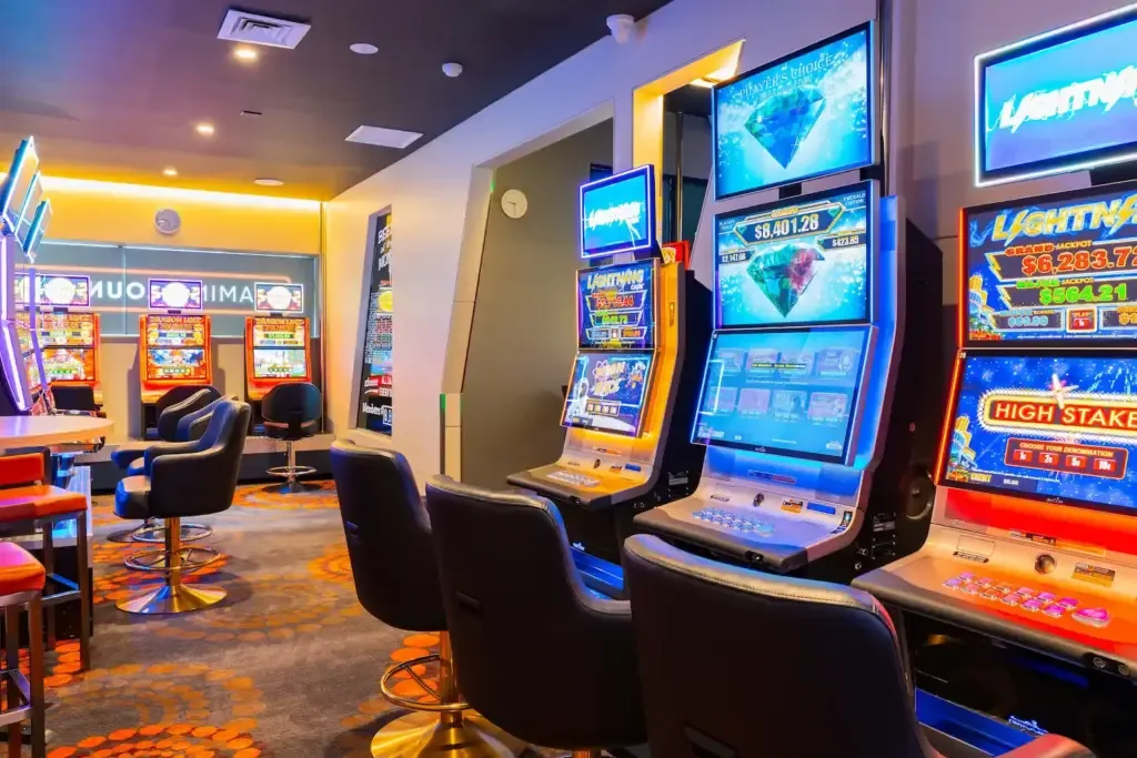 Espacio representativo del hotel: Una sala de juegos bien iluminada con máquinas electrónicas y asientos.