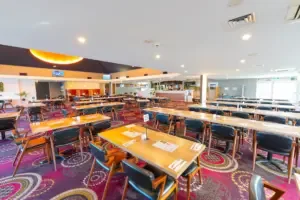 Espacio representativo del hotel: Un comedor con mesas y asientos bajo luces brillantes en el techo.