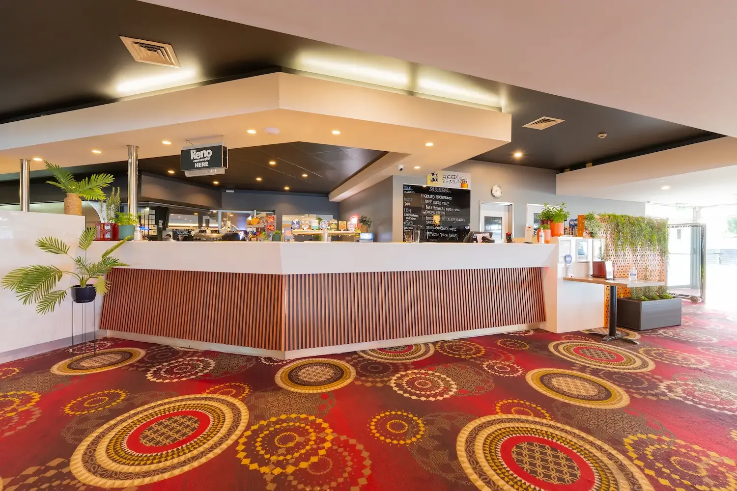 Espacio representativo del hotel: Un mostrador de recepción de hotel se alza sobre una alfombra roja estampada.