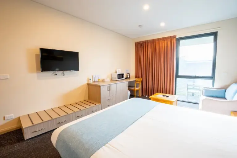 Espacio representativo del hotel: Un dormitorio con cama, televisor en la pared y escritorio junto a la ventana.