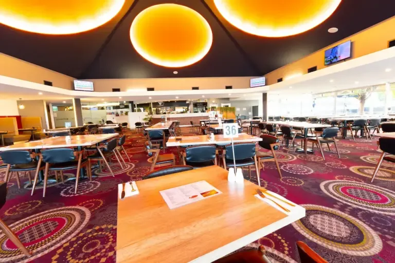 Espacio representativo del hotel: Un amplio comedor con mesas y asientos bajo grandes luces circulares en el techo.