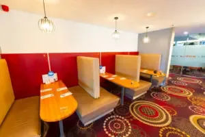 Espacio representativo del hotel: Una zona de comedor con mesas, asientos y paneles rojos en la pared.