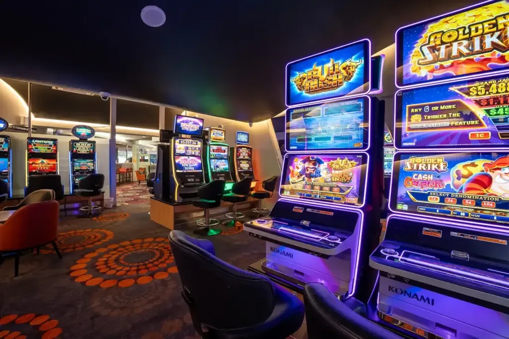Espacio representativo del hotel: Una zona de juegos recreativos iluminada con filas de máquinas tragamonedas coloridas.