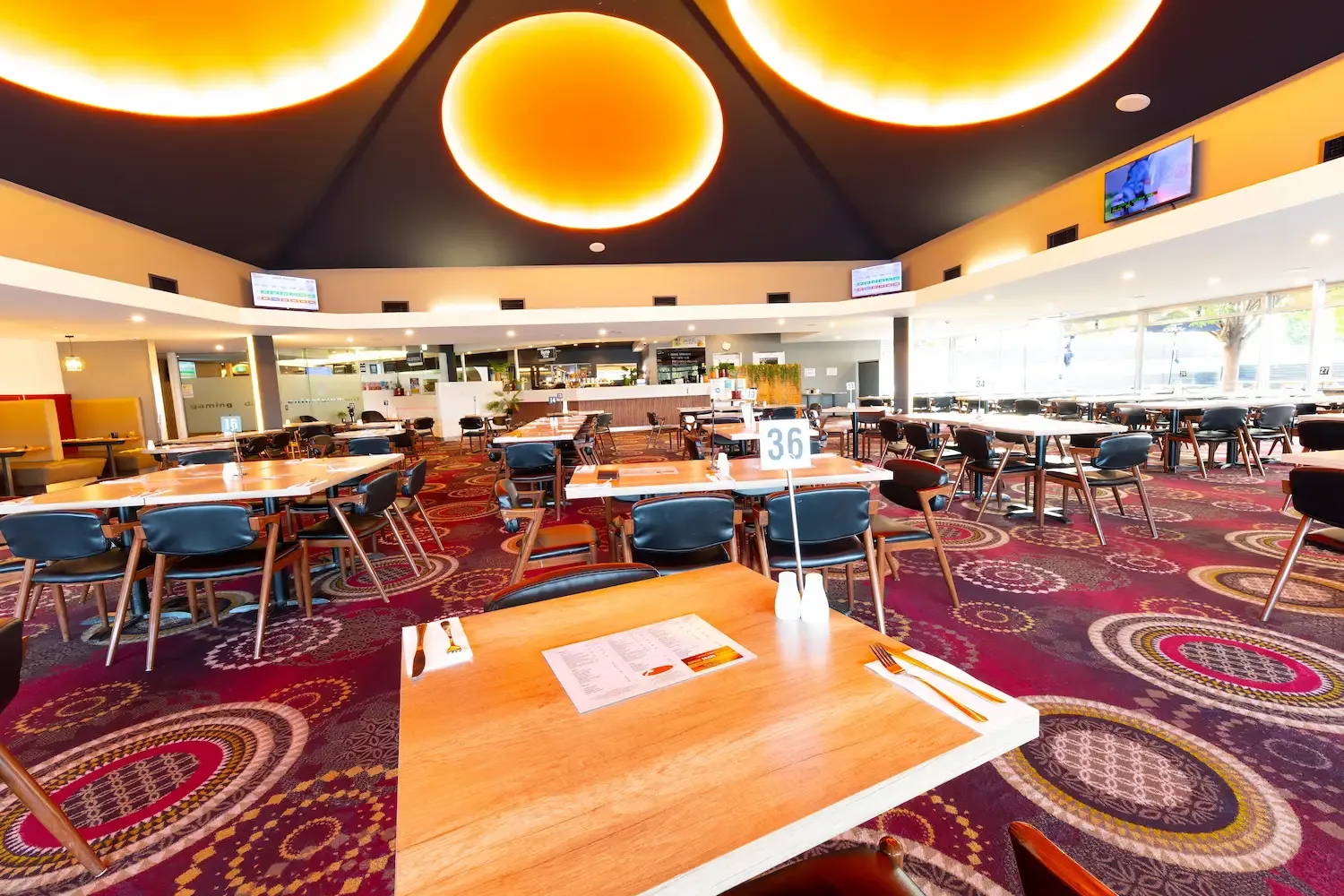 Espacio representativo del hotel: Un comedor con mesas y sillas bajo grandes luces circulares en el techo.