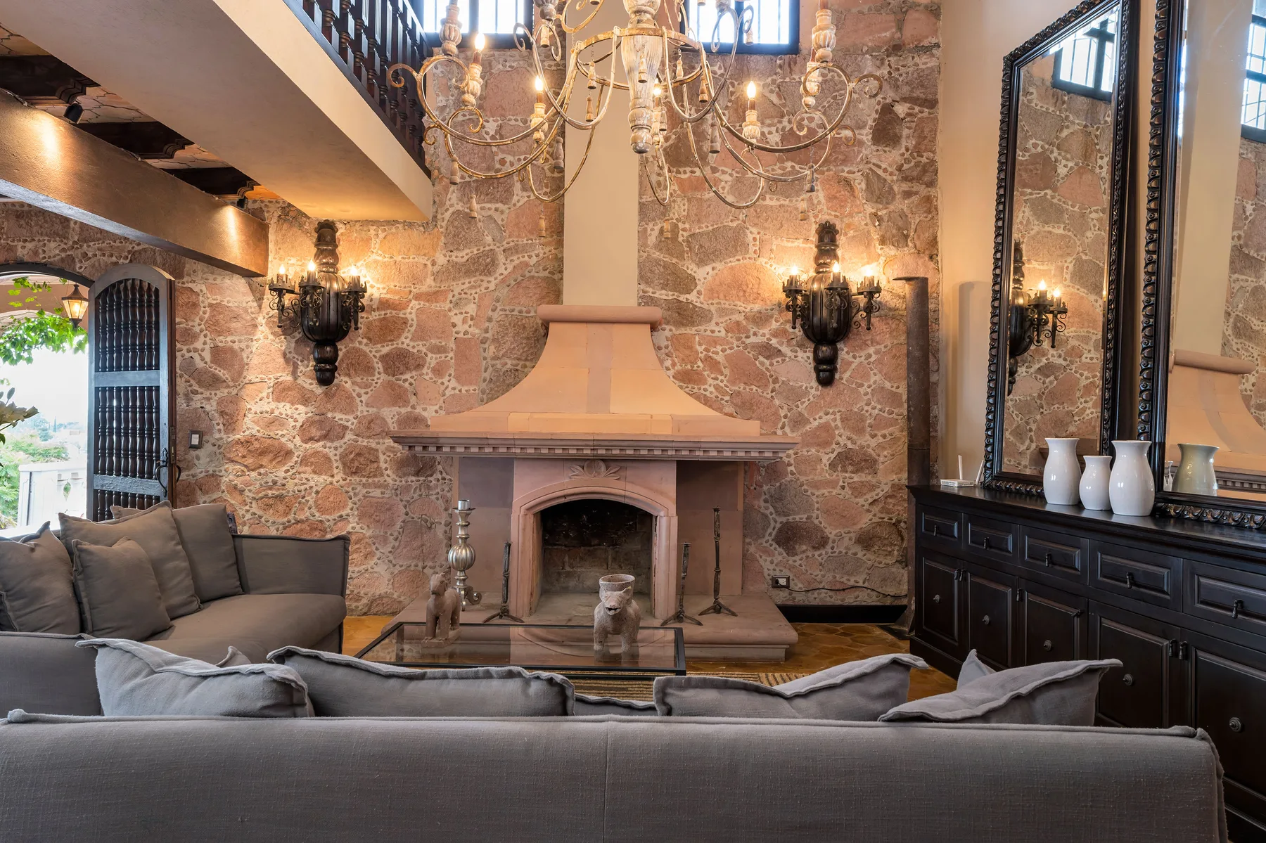 A living room with seating arranged around a stone fireplace.