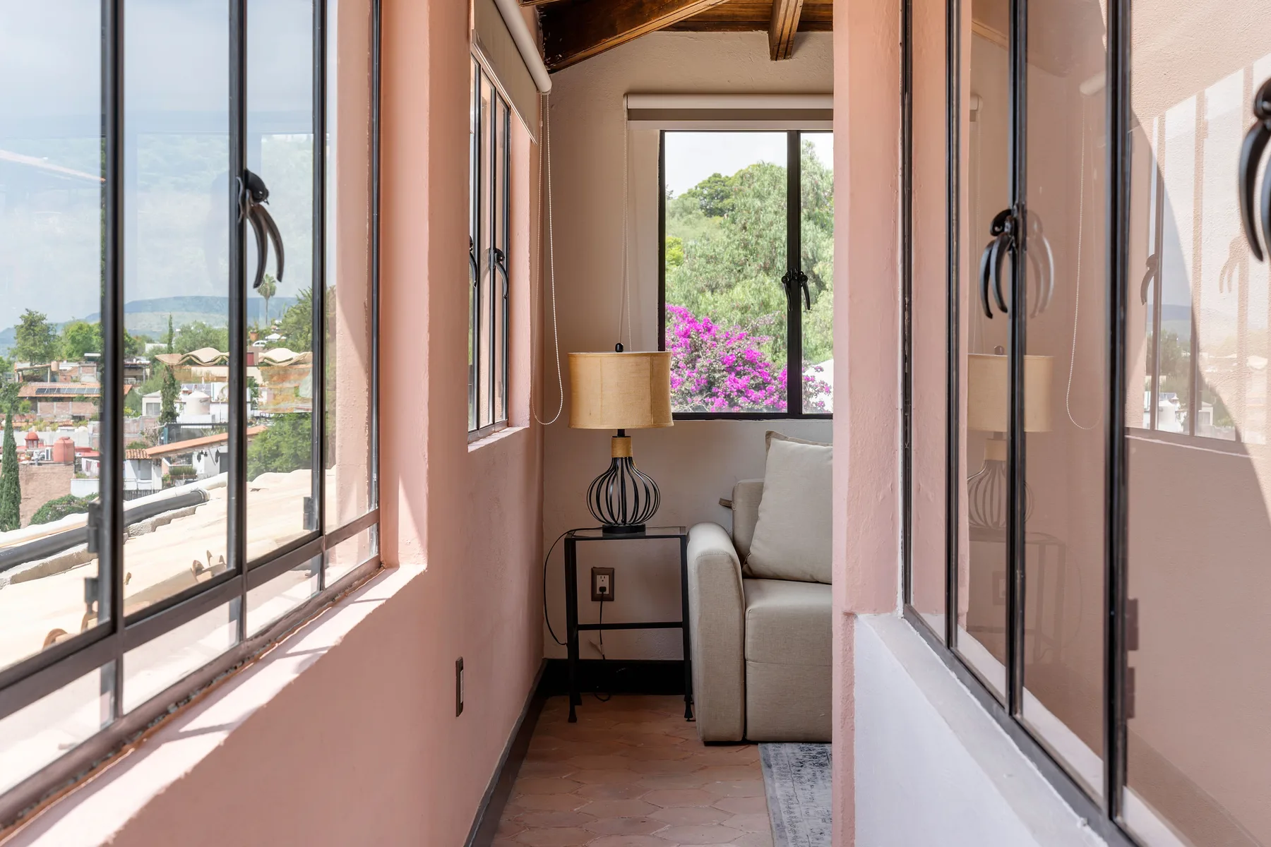 A narrow sitting area with a light-colored sofa and a window overlooking greenery.