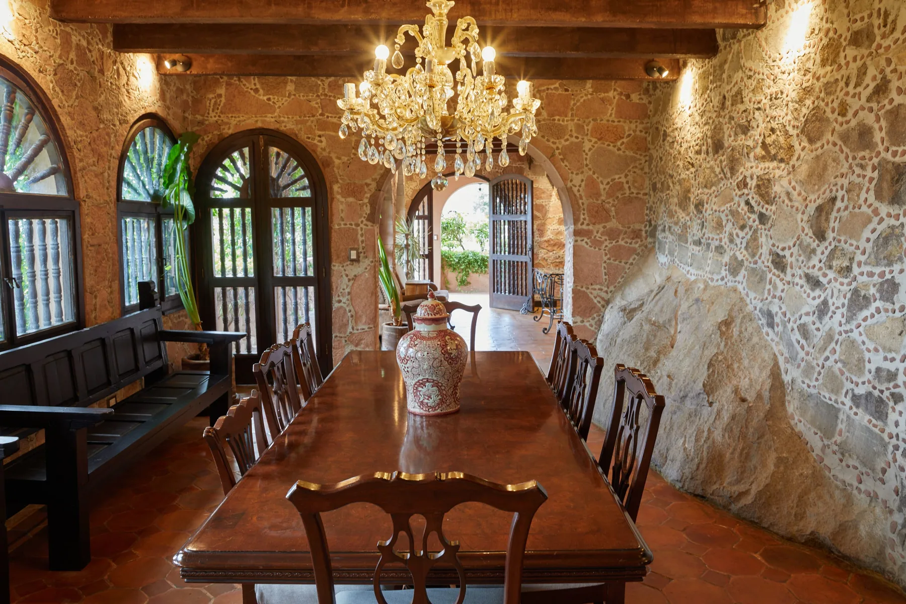A rustic dining room with a long wooden table and chandelier.