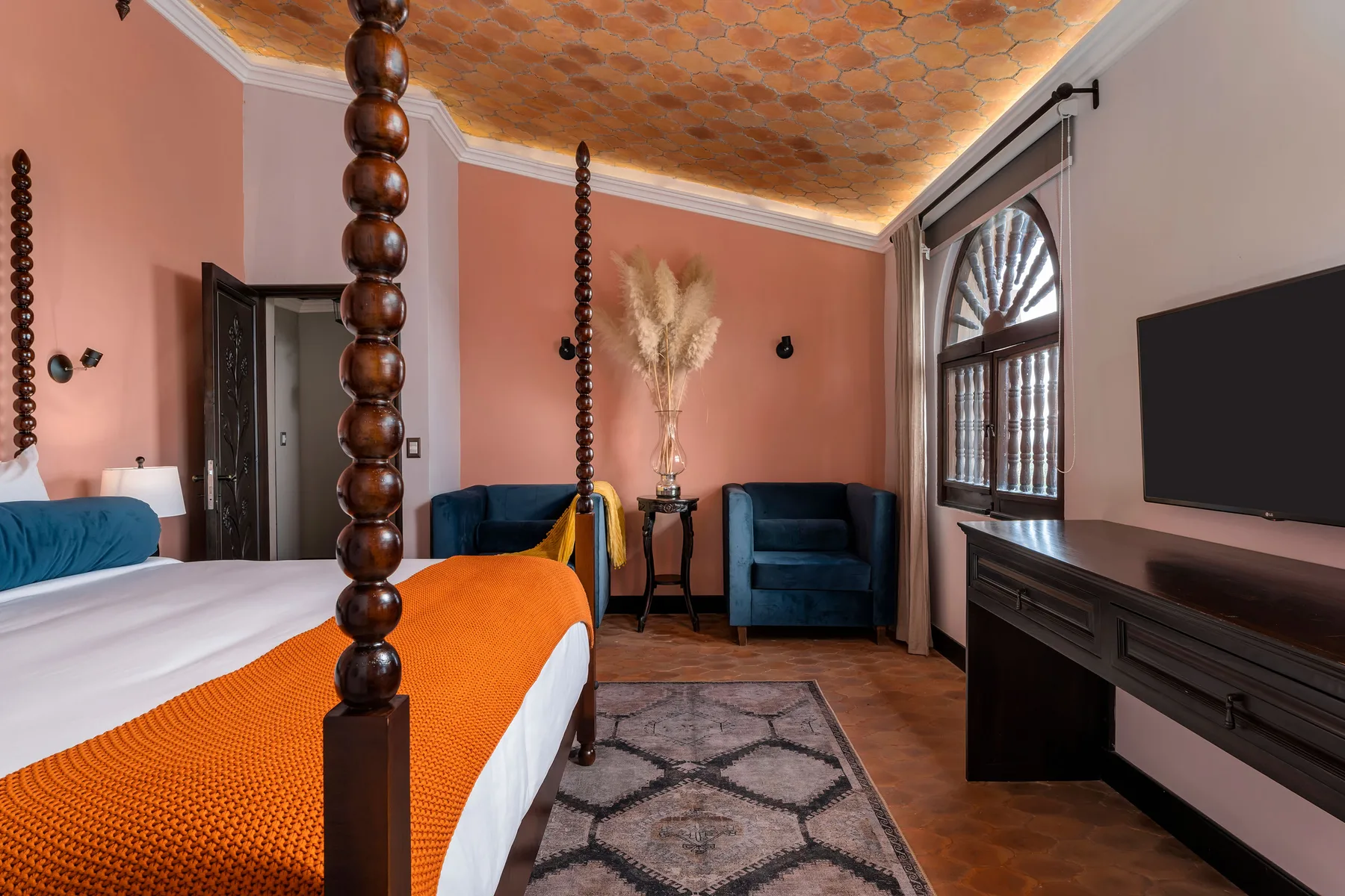 A bedroom with a bed, seating, and an arched window.