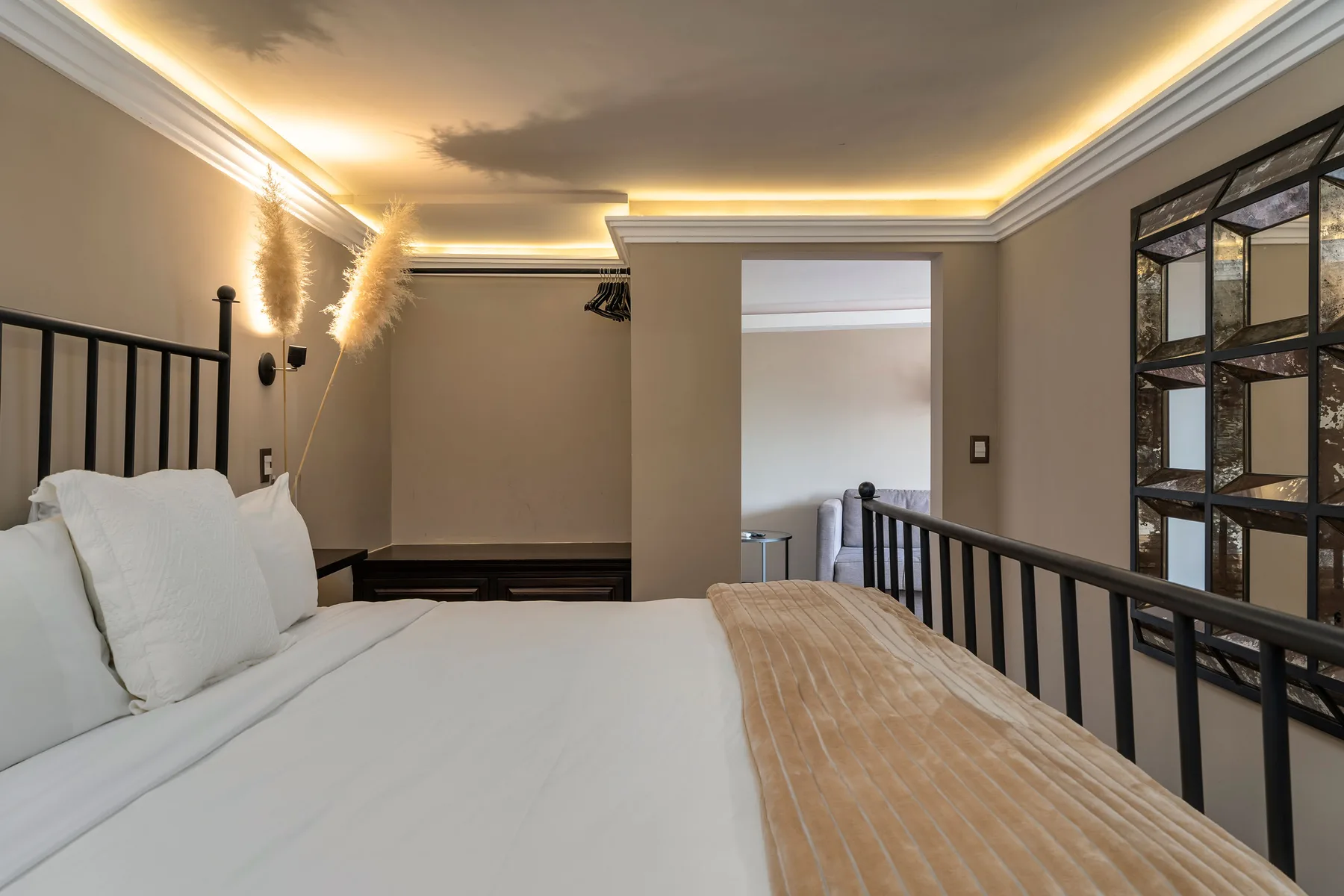 A bedroom with a large bed, white linens, and warm recessed ceiling lighting.