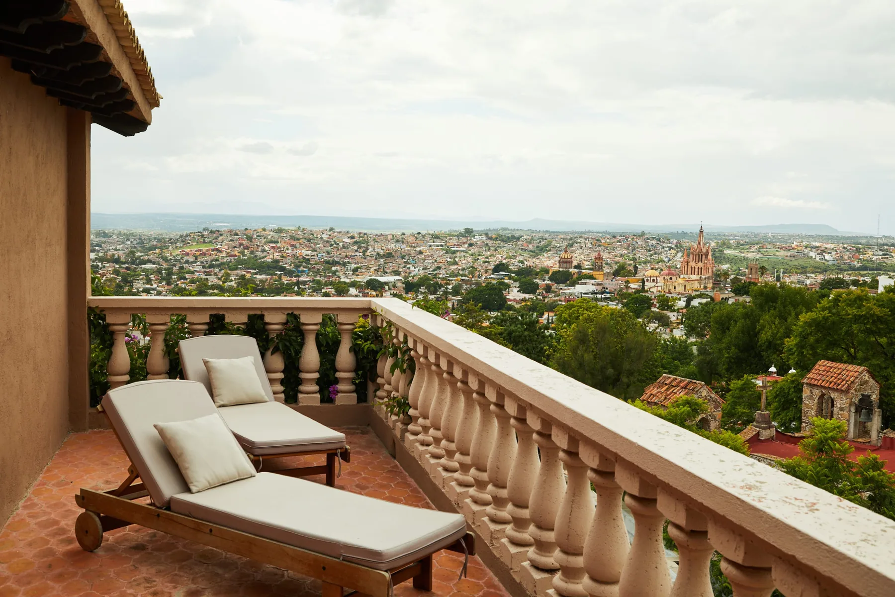 A terrace with cushioned lounge seating overlooks a sprawling city.