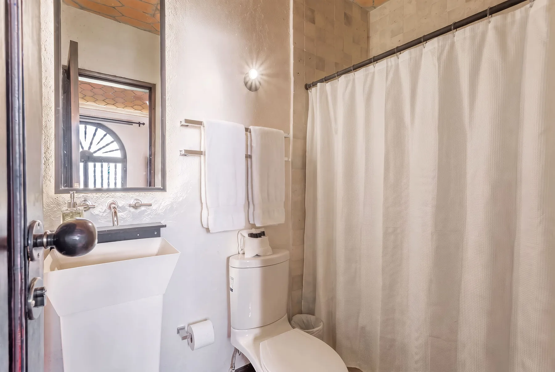 A bathroom with a sink, toilet, and curtained shower.
