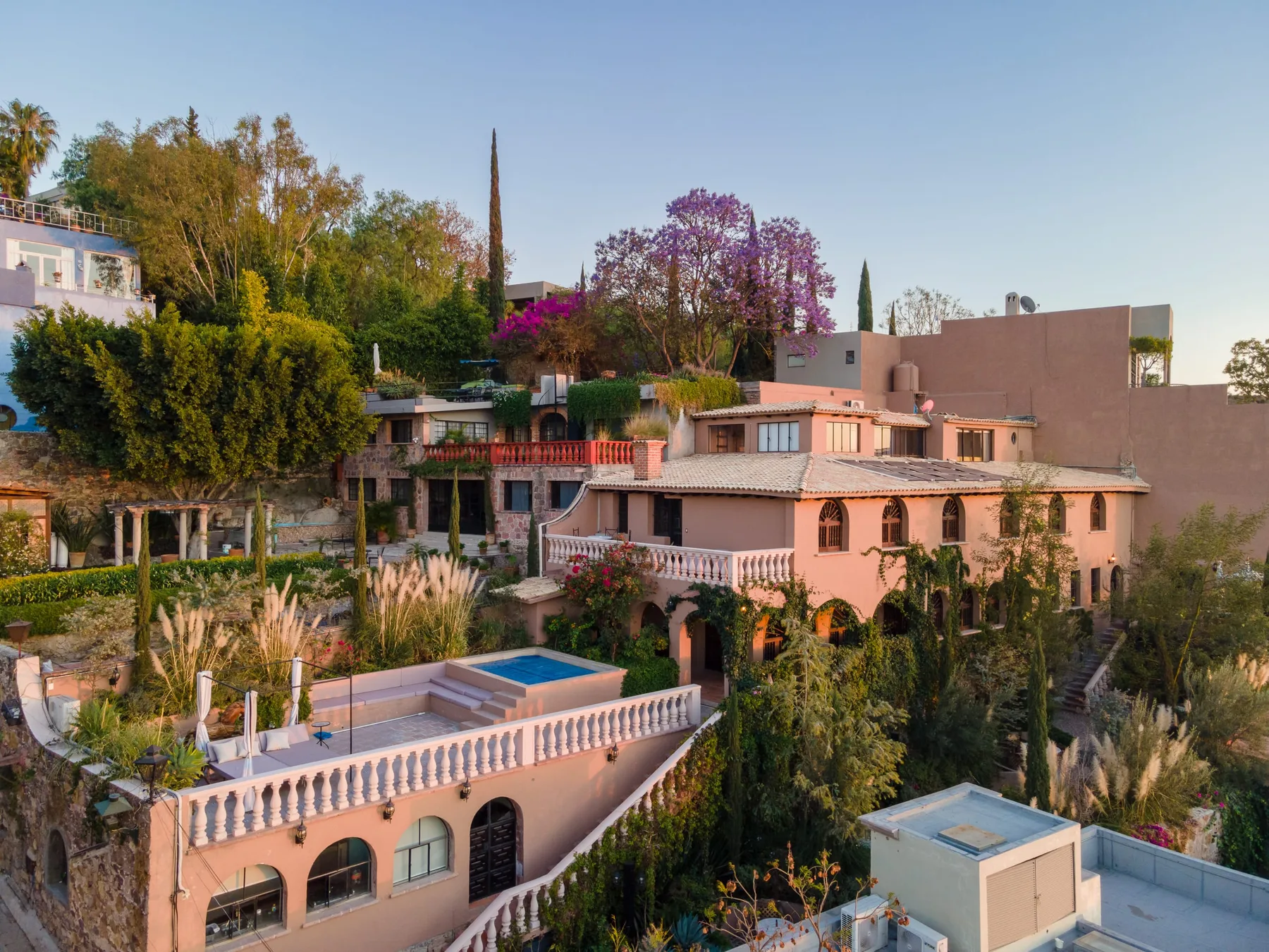 A pink stucco building overlooks a landscaped courtyard with a swimming pool.