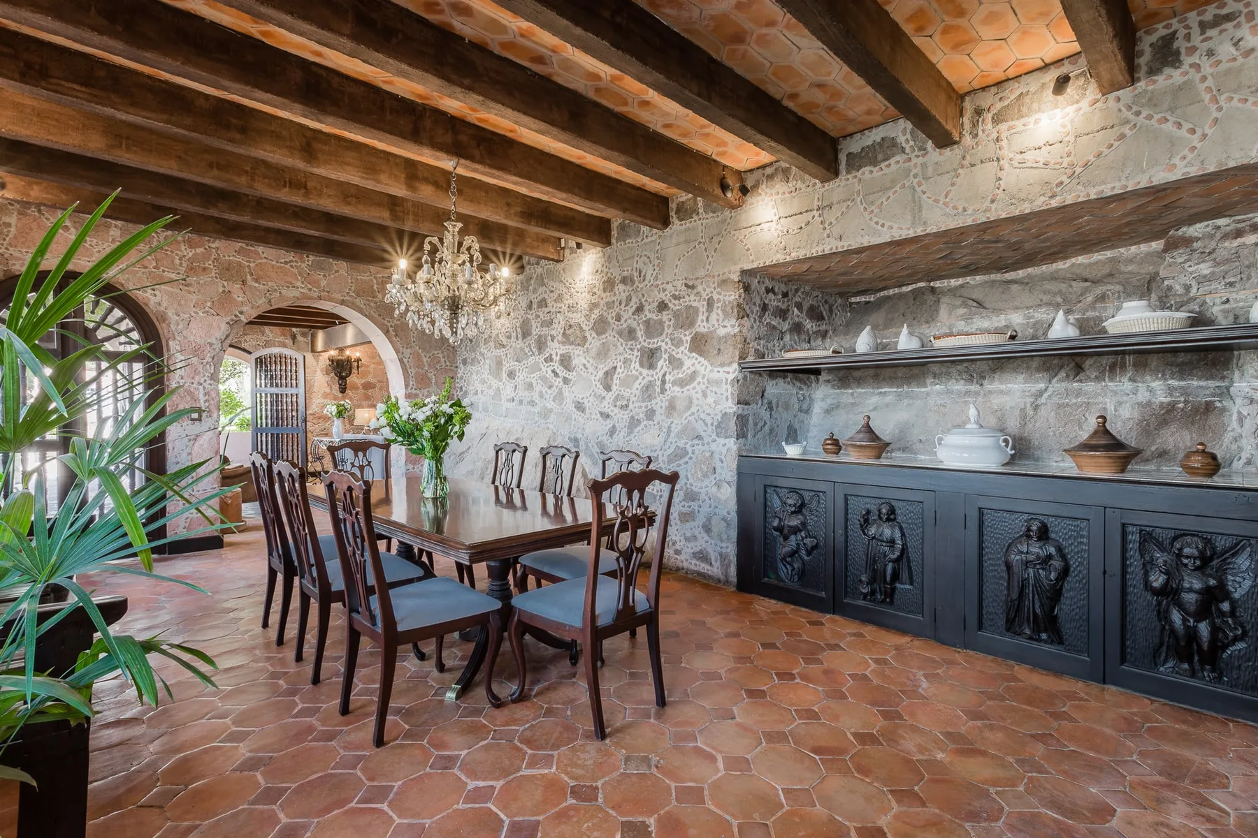 A rustic dining room with a long wooden table and built-in display shelves.