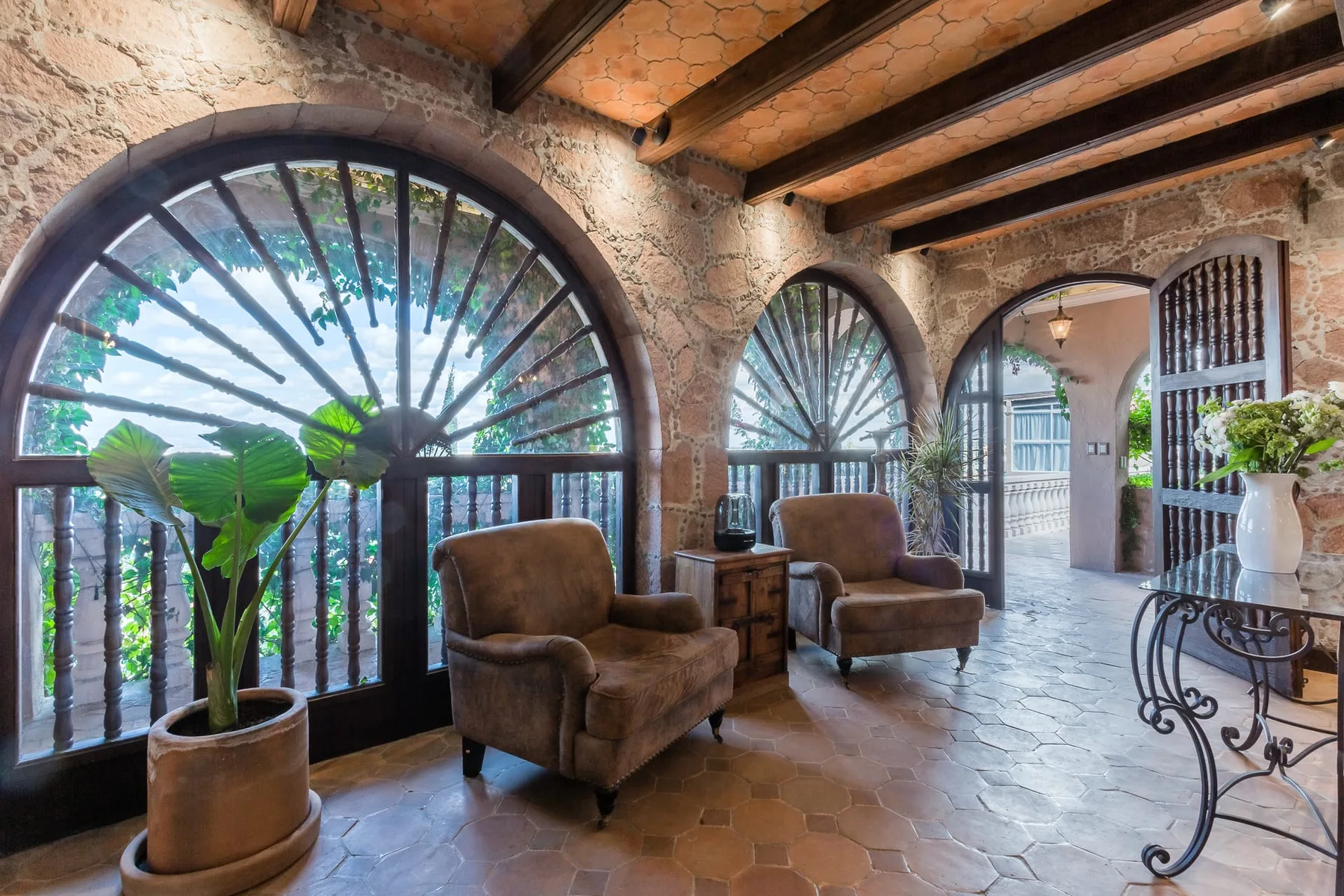 A stone entry hall with arched windows and upholstered seating.